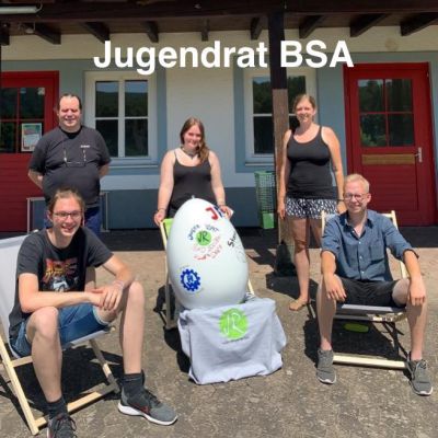 Junge Menschen in Sonnenstühlen vor einem Gebäude