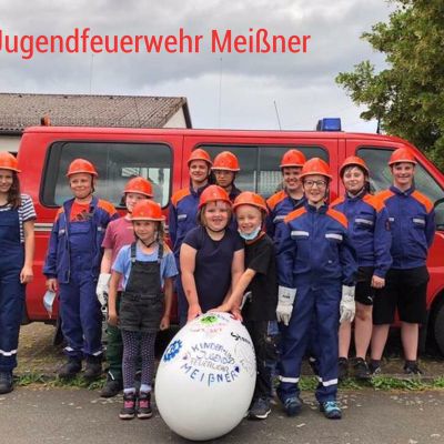 Kinder der Jugendfeuerwehr mit einem Ei vor einem Feuerwehrauto
